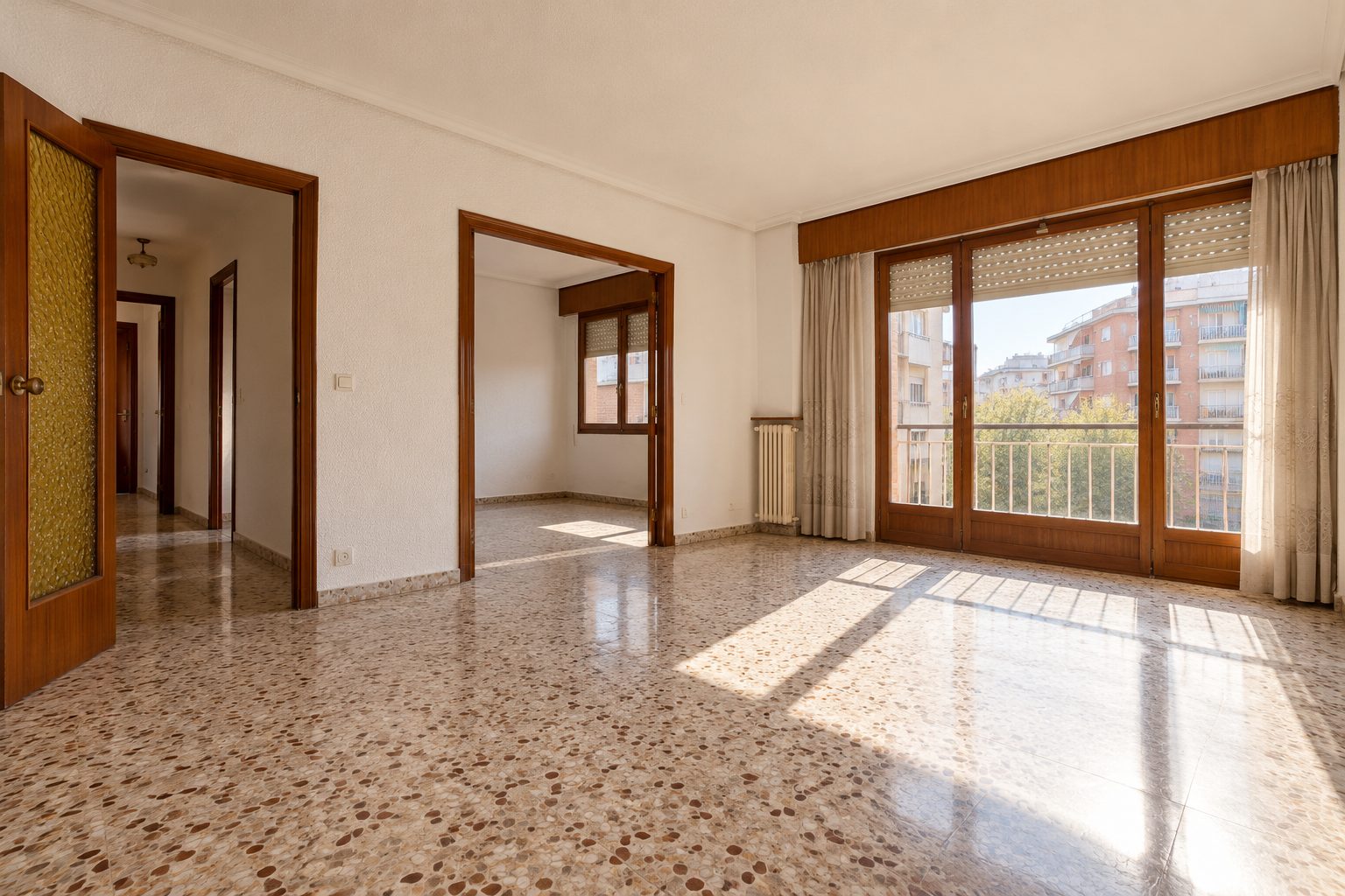 Salón vacío de un piso de época con suelo de terrazo, carpintería de madera y luz natural